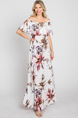 woman wearing a white off-the-shoulder maxi dress with a large floral print in shades of pink and purple