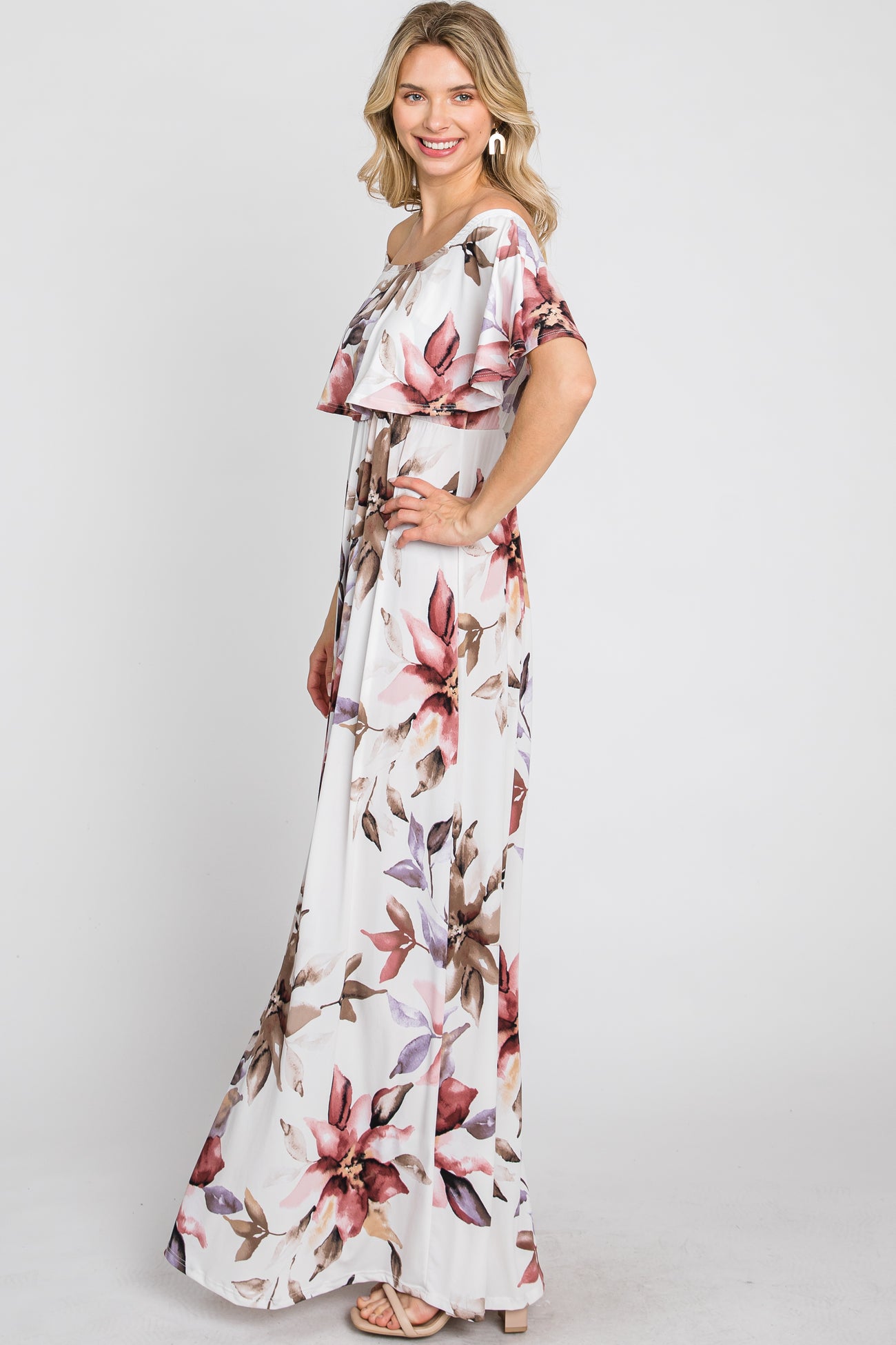 woman wearing a white floral maxi dress with an off-the-shoulder design and ruffled details