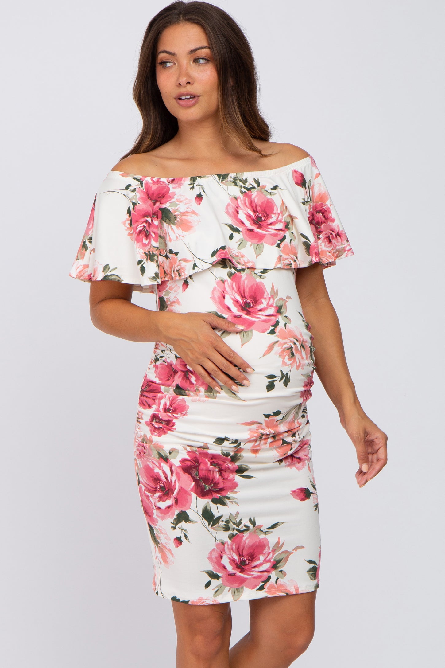 woman wearing a white floral off-the-shoulder maternity dress with ruching and a visible baby bump