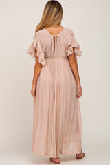 woman wearing a blush pink maternity maxi dress with ruffled sleeves and an adjustable tie back detail