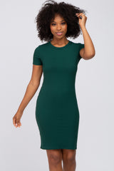 woman with curly hair wearing a short sleeve dark green ribbed bodycon dress against a white background