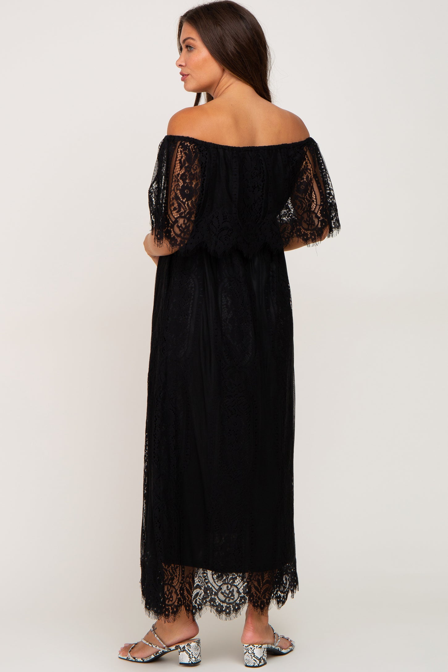 woman wearing a black off the shoulder lace maxi dress and snakeskin print heels