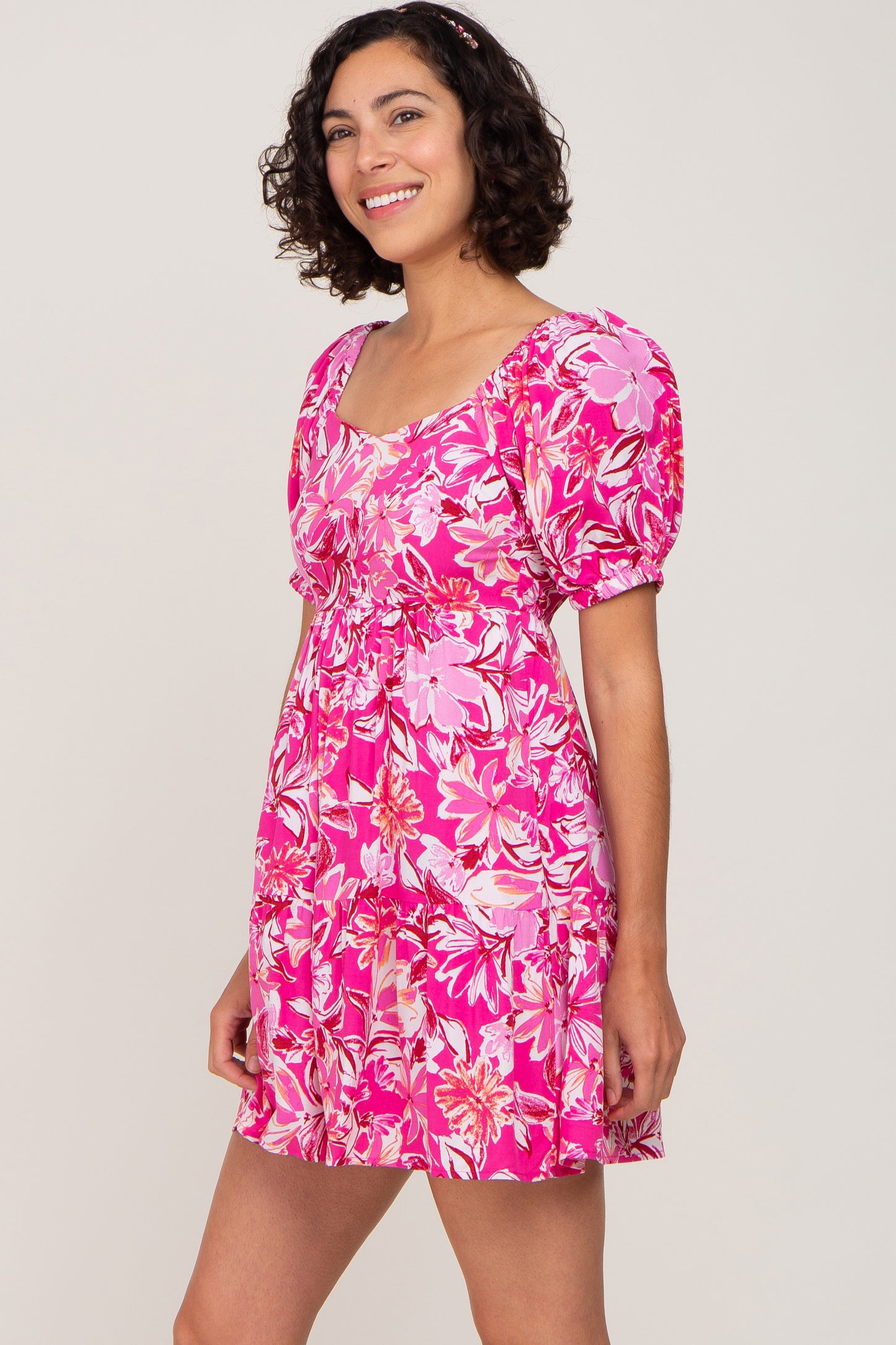 woman wearing a pink floral puff sleeve mini dress with a tiered skirt and sweetheart neckline