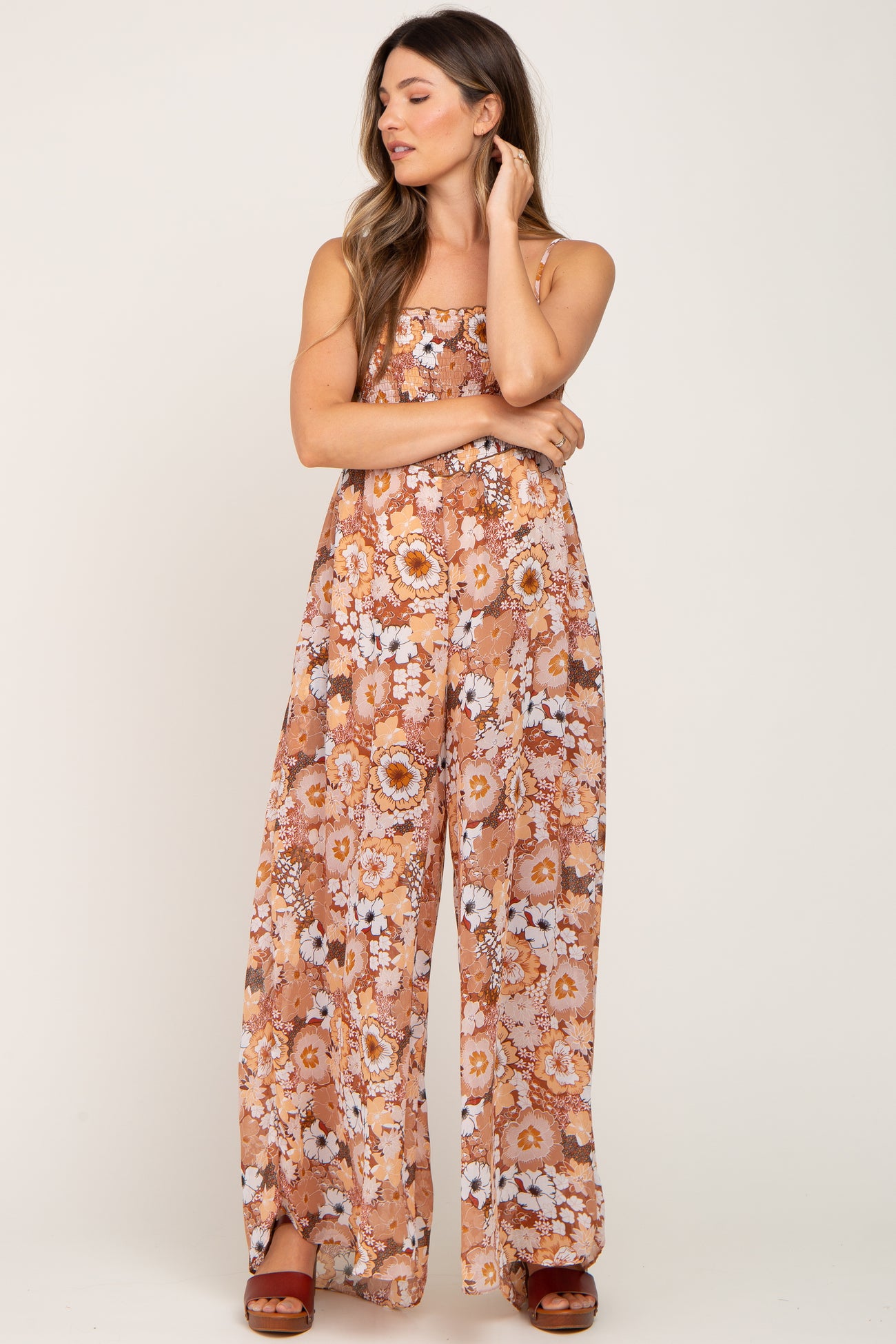 woman wearing a brown floral print wide leg jumpsuit with smocked bodice and platform sandals