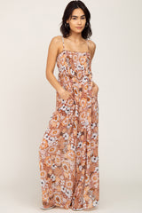 Woman wearing a floral print wide leg jumpsuit with spaghetti straps and pockets against a white background