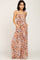 Woman wearing a floral print wide leg jumpsuit with spaghetti straps and pockets against a white background