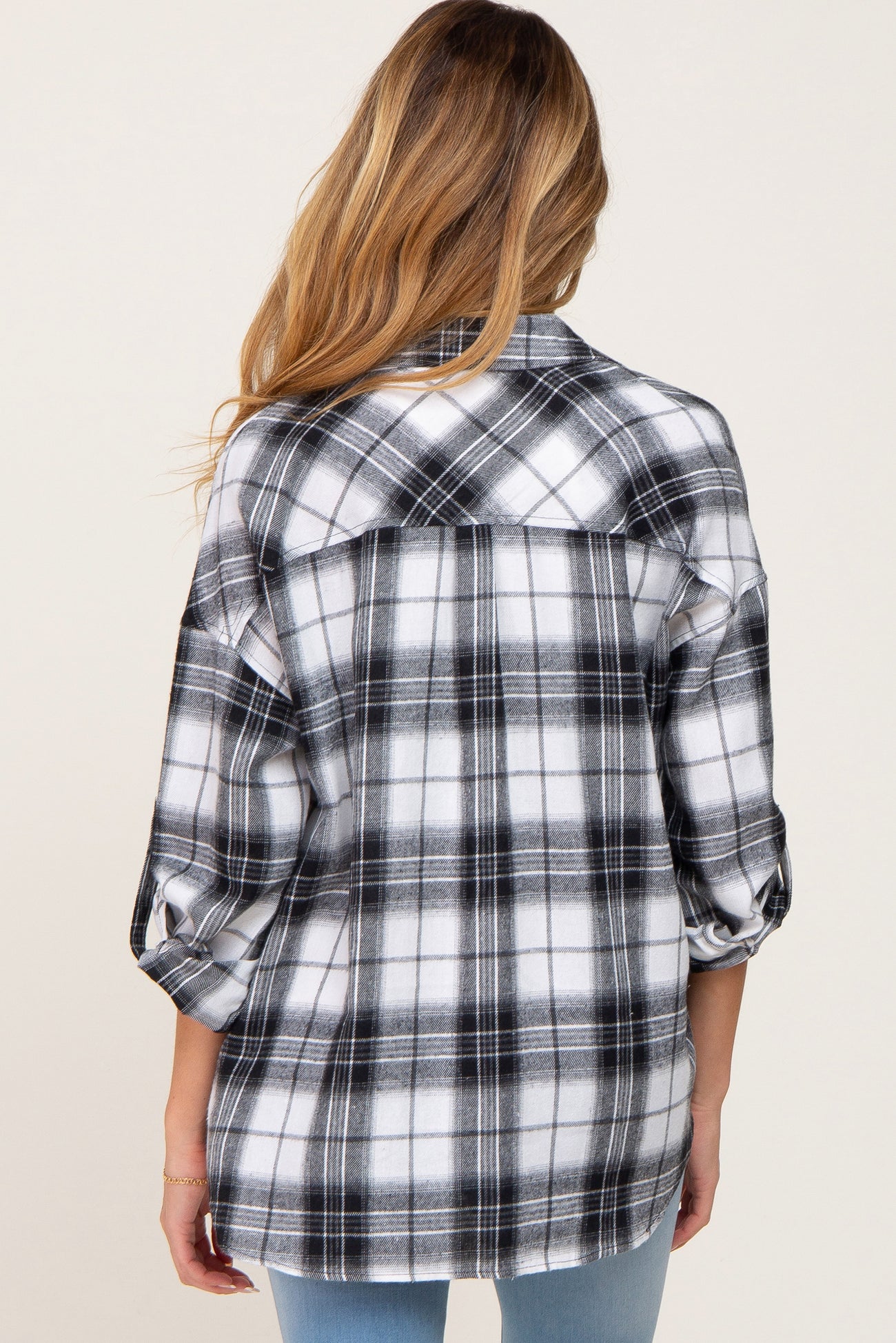 back view of a woman wearing a black and white plaid flannel shirt with rolled sleeves