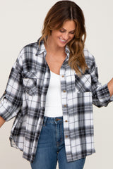 woman wearing an oversized black and white plaid flannel shirt over a white tank top and blue jeans