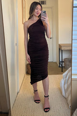 woman wearing a dark brown one-shoulder ruched midi dress and black strappy heels taking a mirror selfie