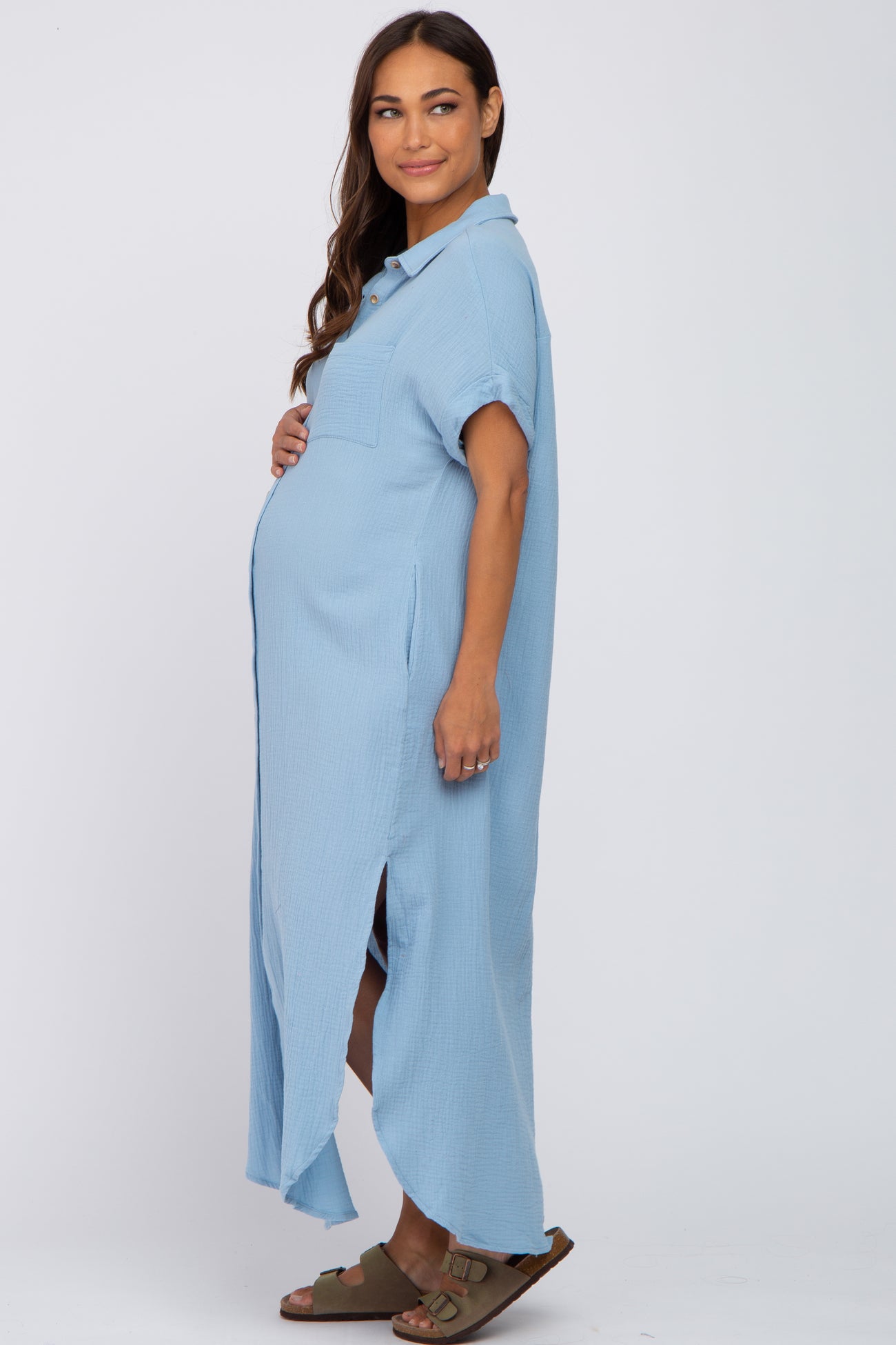 woman wearing a light blue maternity button-up dress with a pocket and side slits, showing her baby bump