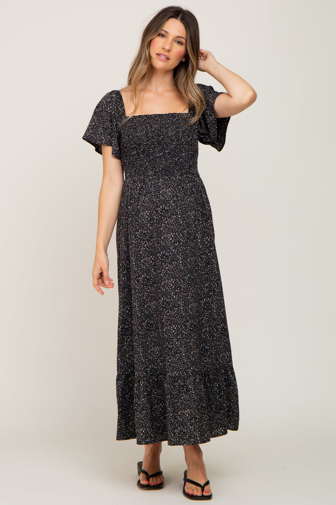 woman wearing a black floral smocked maternity maxi dress with flutter sleeves and square neckline