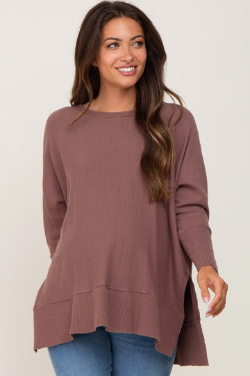 woman wearing a mauve oversized maternity sweater with side slits, styled with blue jeans