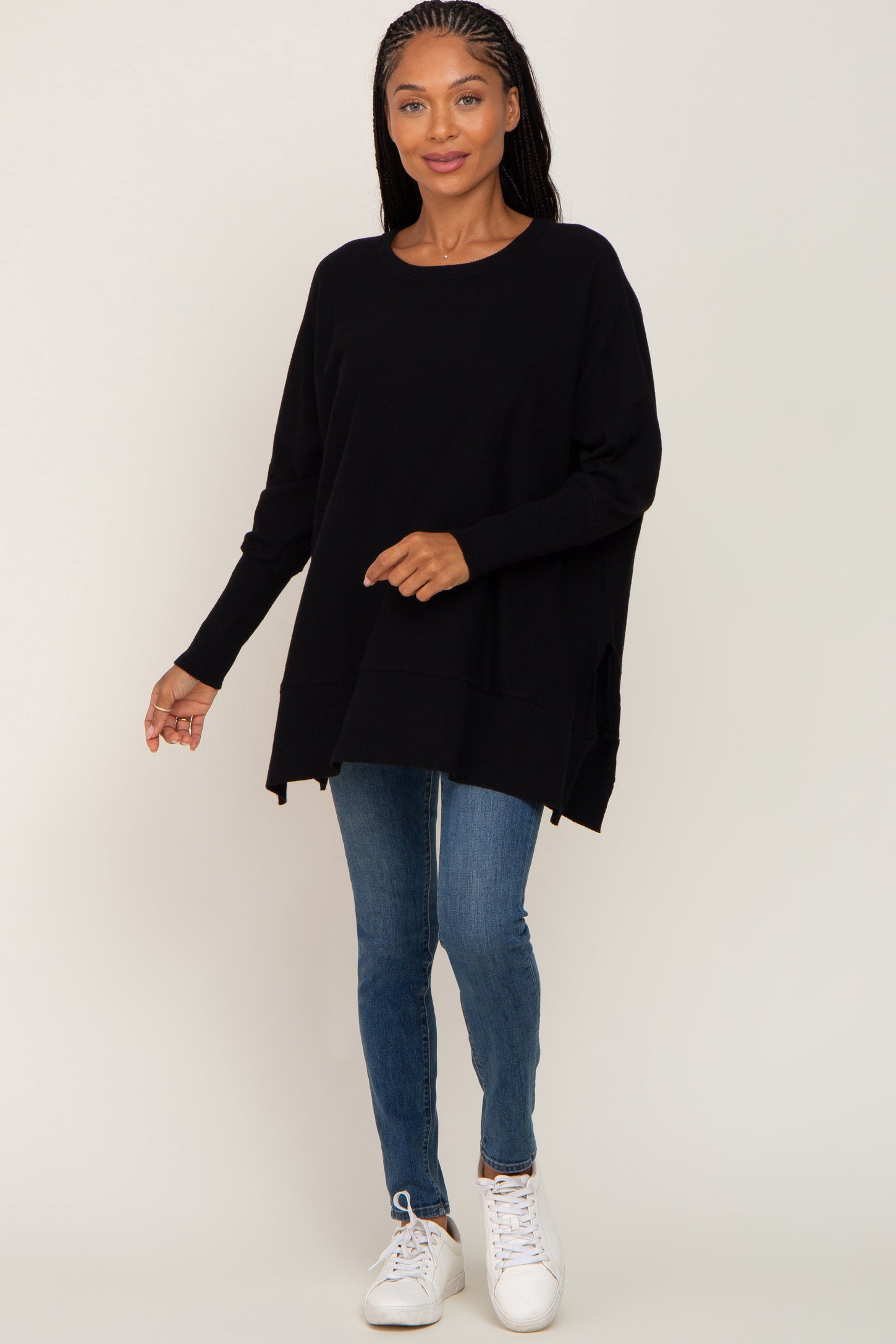 woman wearing oversized black crewneck sweater with blue skinny jeans and white sneakers