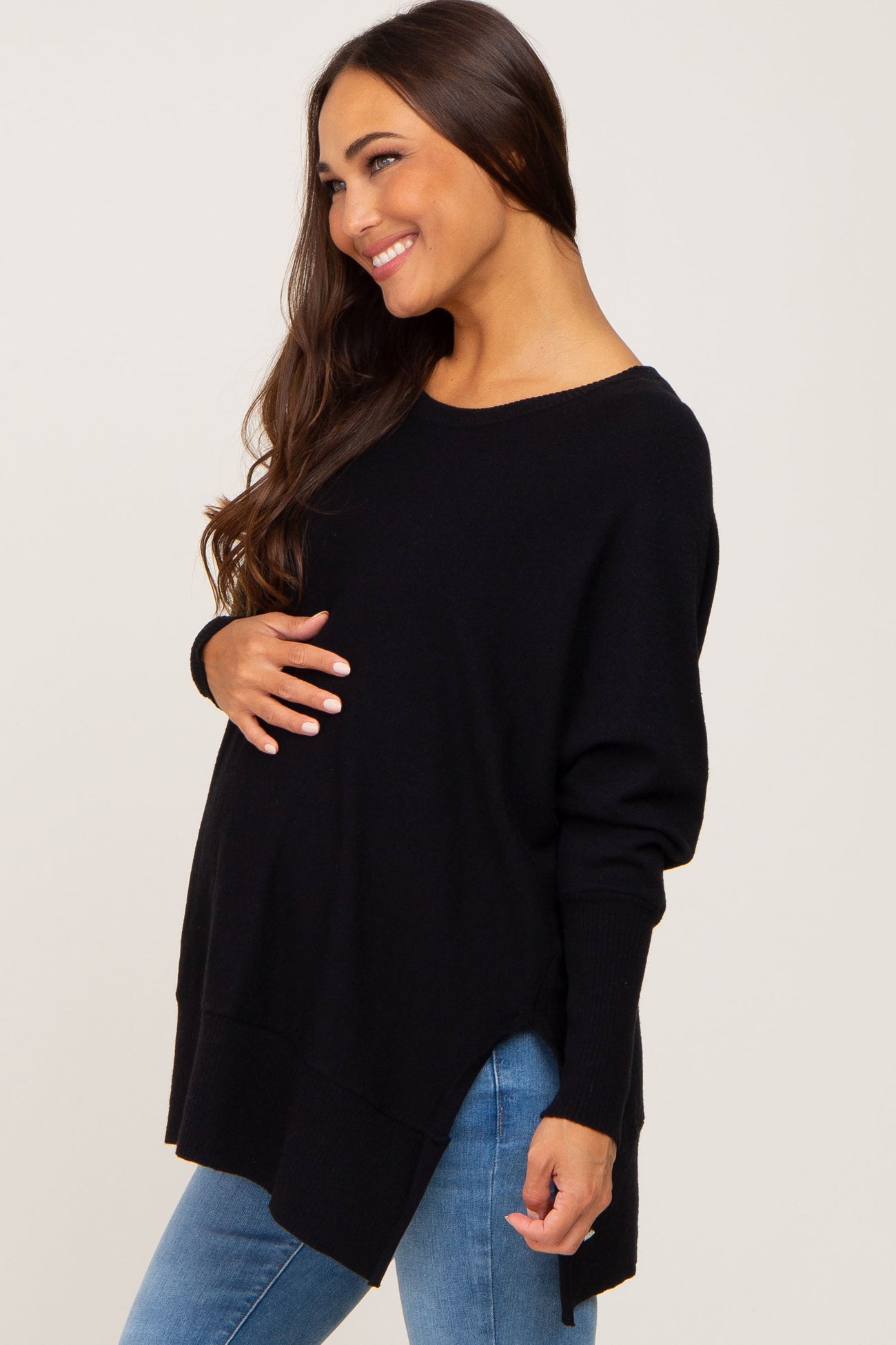 woman wearing a black oversized maternity sweater and holding her baby bump