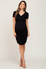 woman wearing a black short sleeve maternity dress with ruching and a visible baby bump