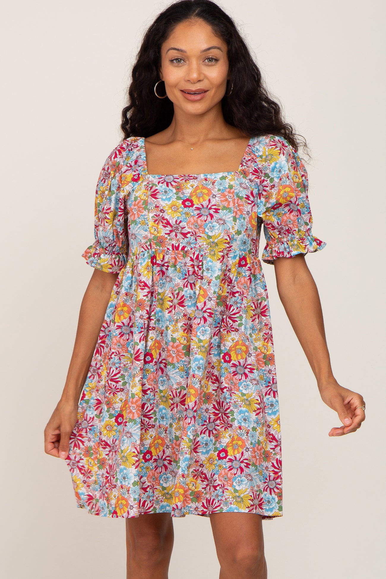 woman wearing a colorful floral print mini dress with puff sleeves and a square neckline