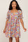 woman wearing a colorful floral print mini dress with puff sleeves and a square neckline