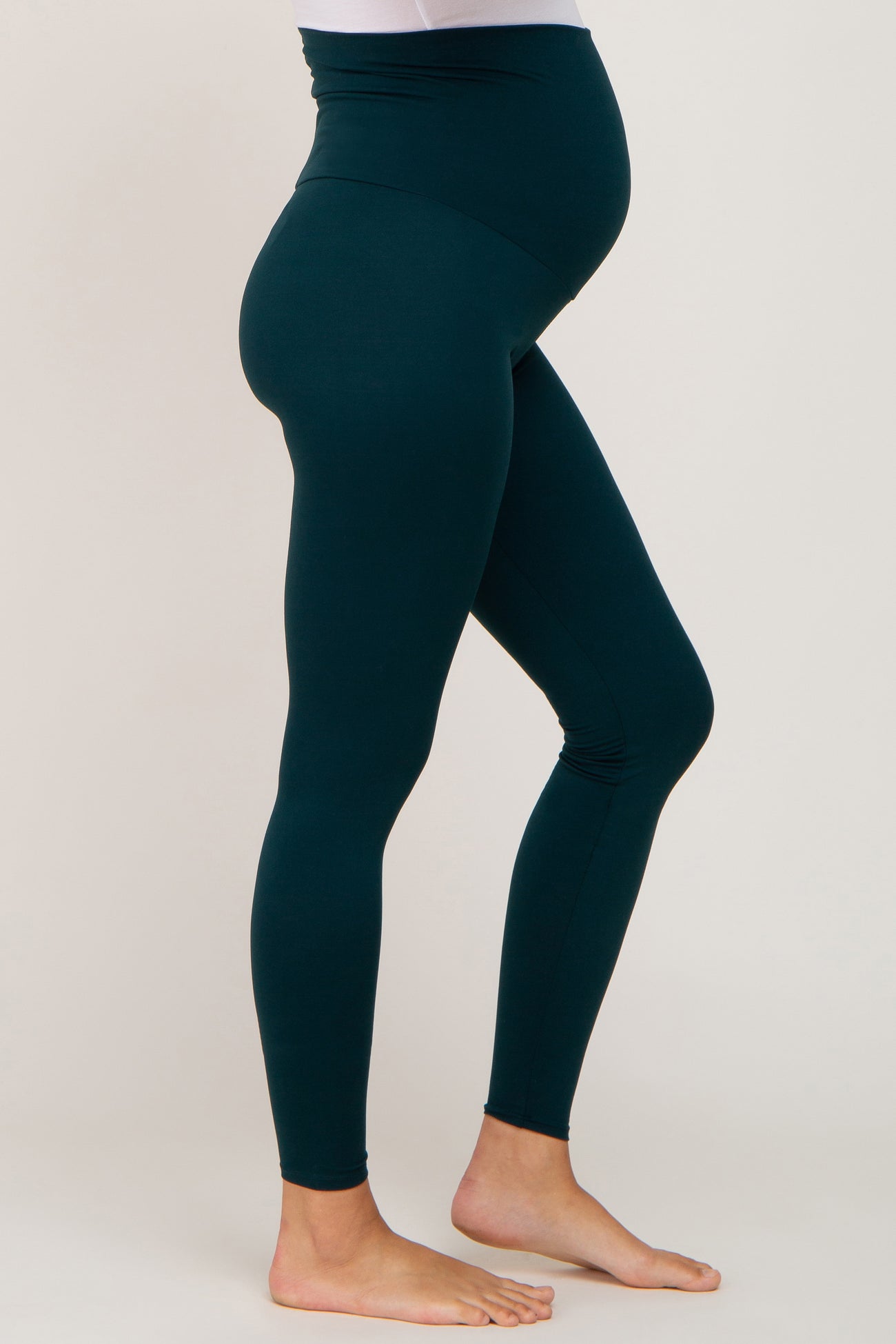 maternity wear in teal high-waisted leggings featuring a fitted style and a visible baby bump