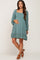 woman wearing a teal long sleeve maternity dress with a ruffled hem and holding her baby bump