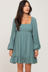woman wearing a teal square neck long sleeve dress with a ruffled hemline