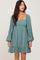 woman wearing a teal square neck long sleeve dress with a ruffled hemline