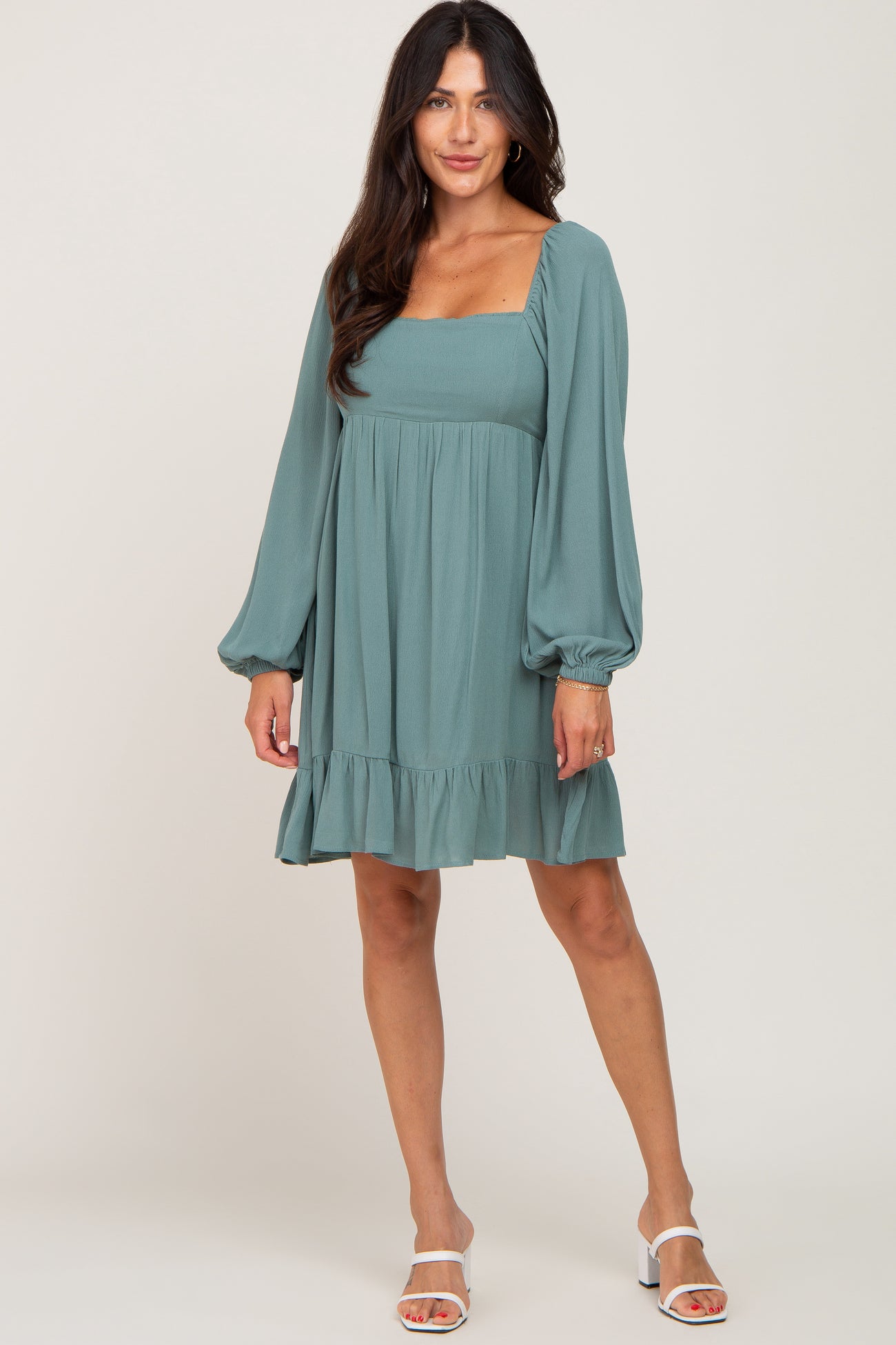 woman wearing a dusty teal long sleeve square neck dress with a ruffled hem and puff sleeves