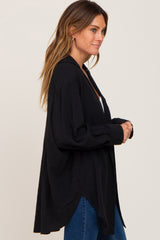 woman wearing a black oversized button-up shirt with long sleeves and side slits, paired with blue jeans