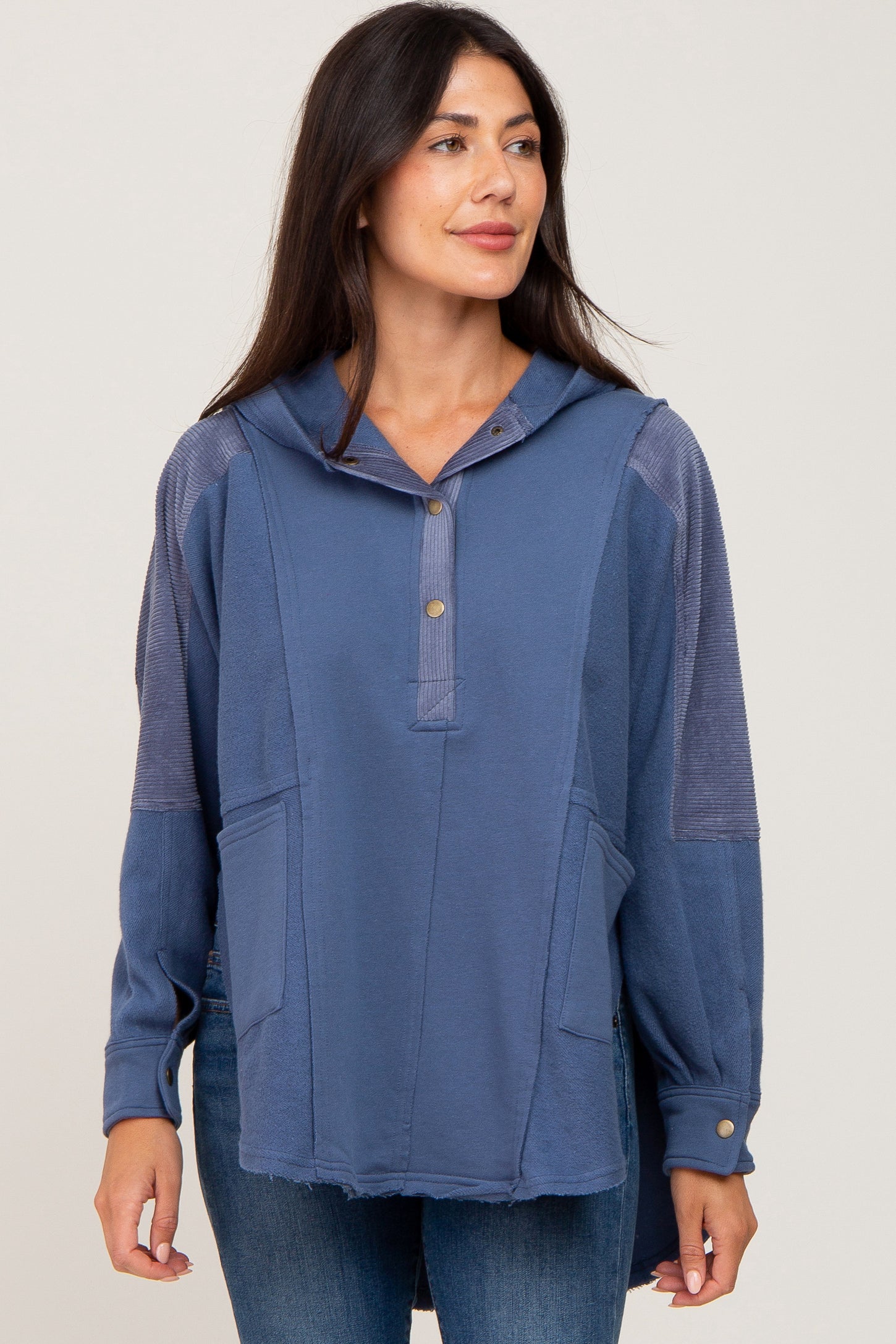 woman wearing a blue hooded pullover with a button placket and front pockets, styled with casual jeans