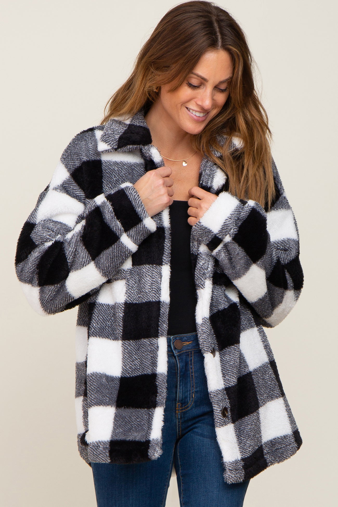 woman wearing a black and white buffalo plaid fuzzy sherpa jacket over a black top and blue jeans