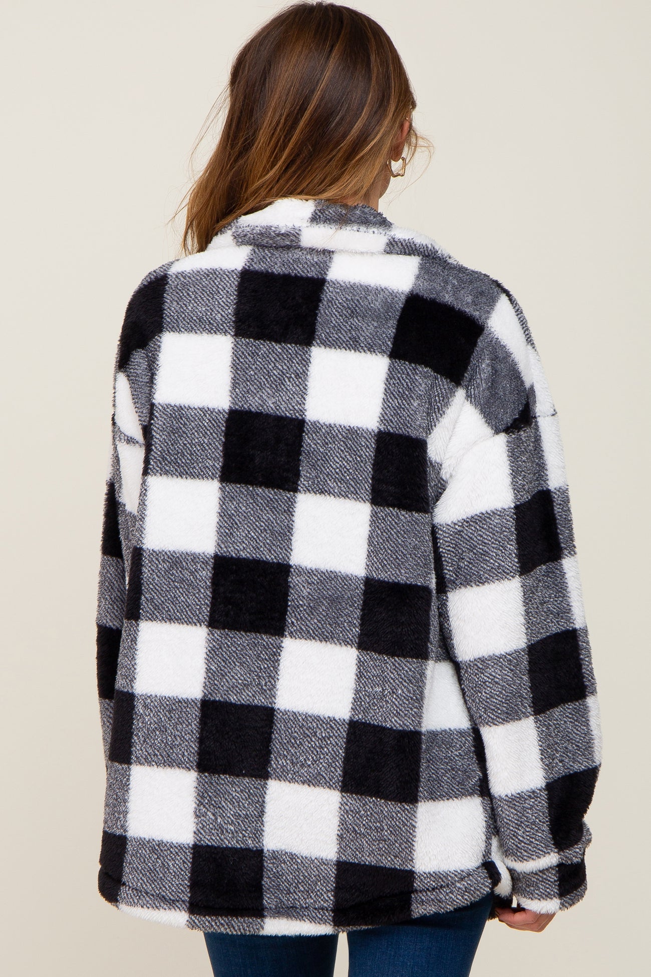 Back view of a woman wearing a black and white buffalo plaid sherpa jacket