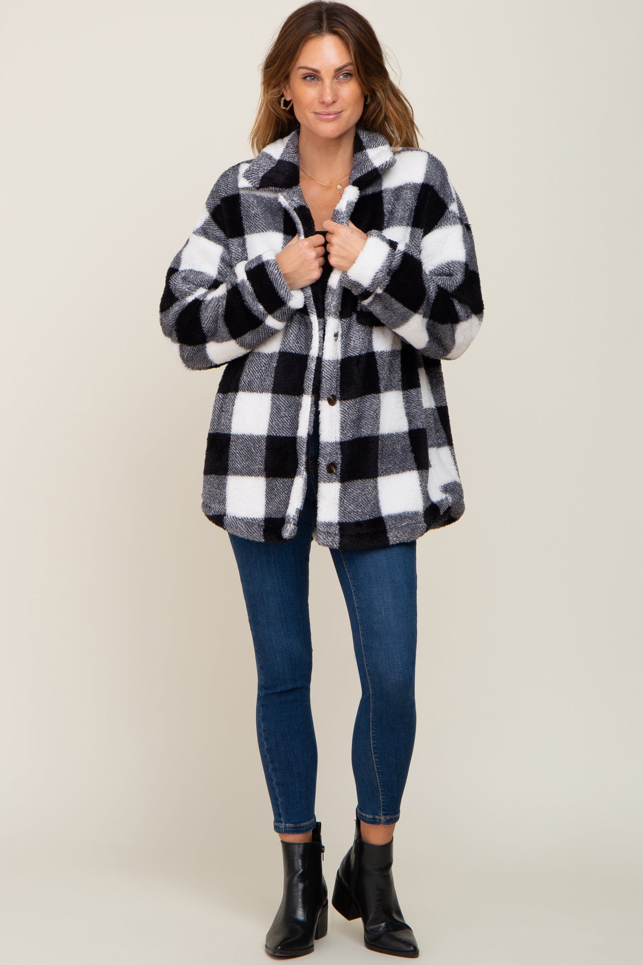 woman wearing black and white buffalo plaid sherpa jacket with blue skinny jeans and black ankle boots