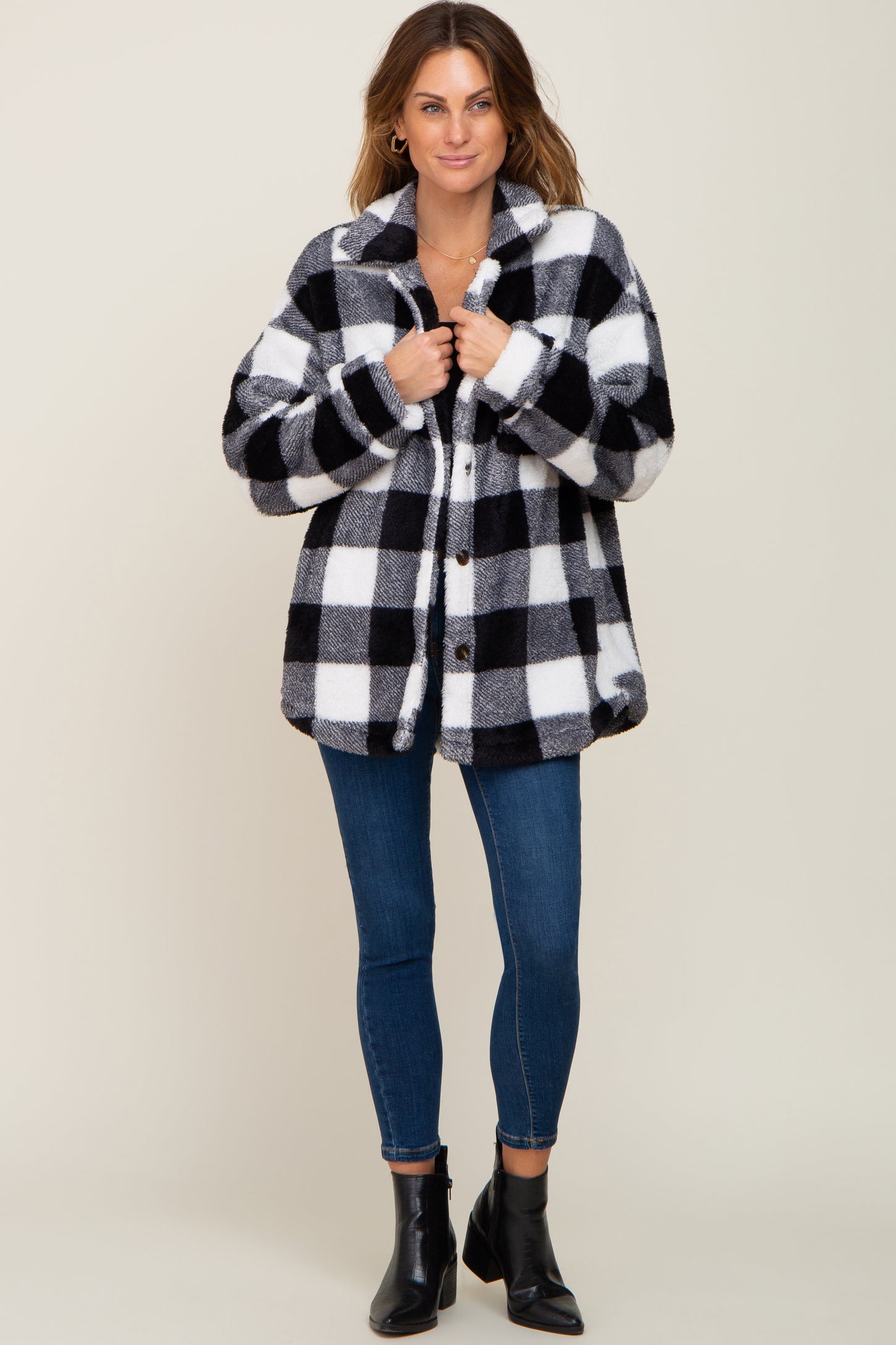 woman wearing black and white buffalo plaid sherpa jacket with blue skinny jeans and black ankle boots