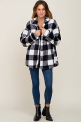 woman wearing black and white buffalo plaid sherpa jacket with blue skinny jeans and black ankle boots