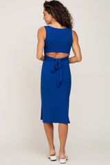 woman wearing a blue ribbed dress with a back cutout and tie detail, viewed from the back