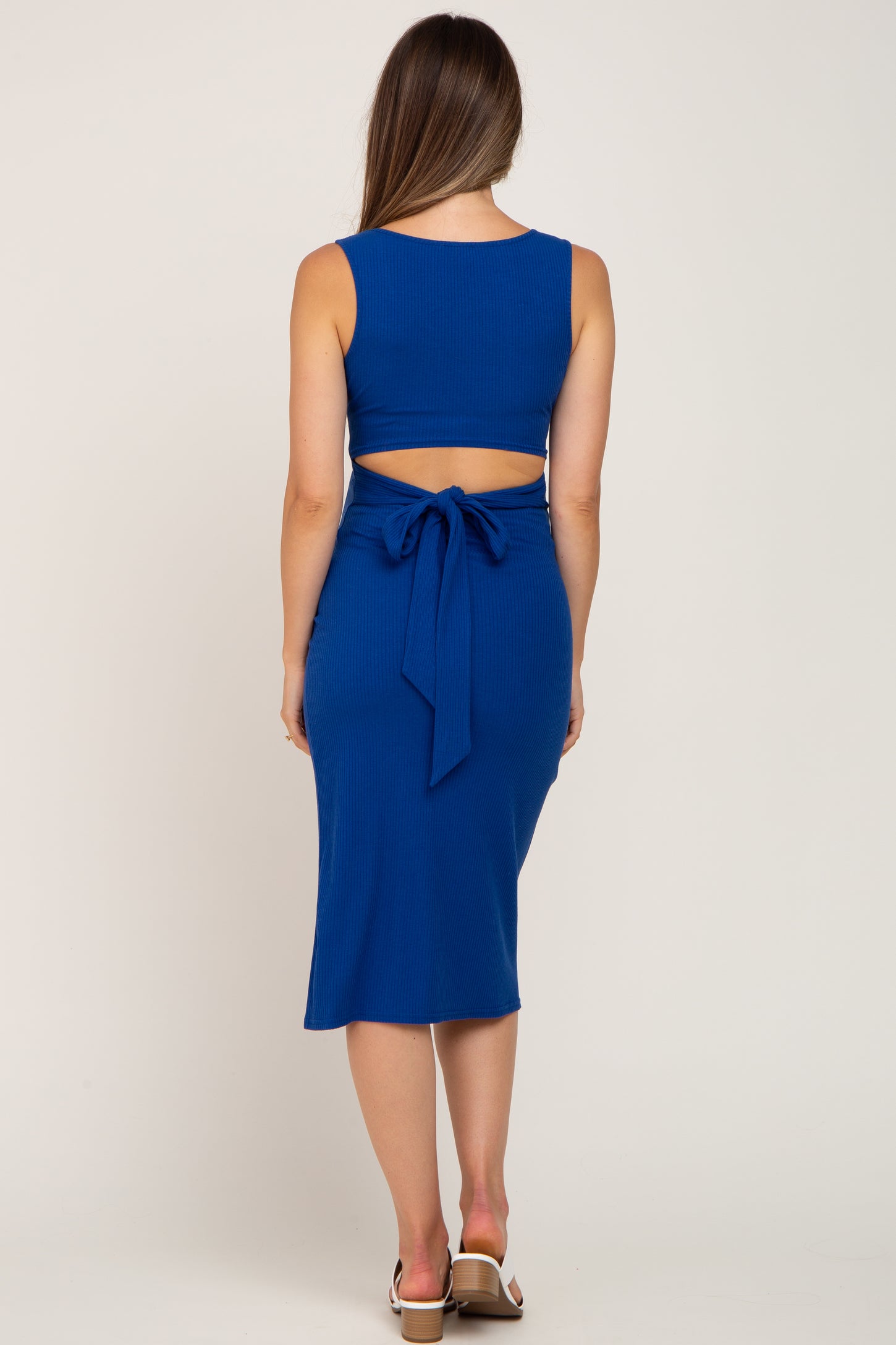 woman wearing a blue ribbed maternity two-piece dress with a fitted crop top and tie detail at the back