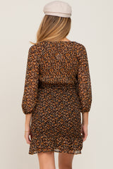 Back view of a woman wearing a brown floral print long sleeve mini dress and a tan newsboy cap