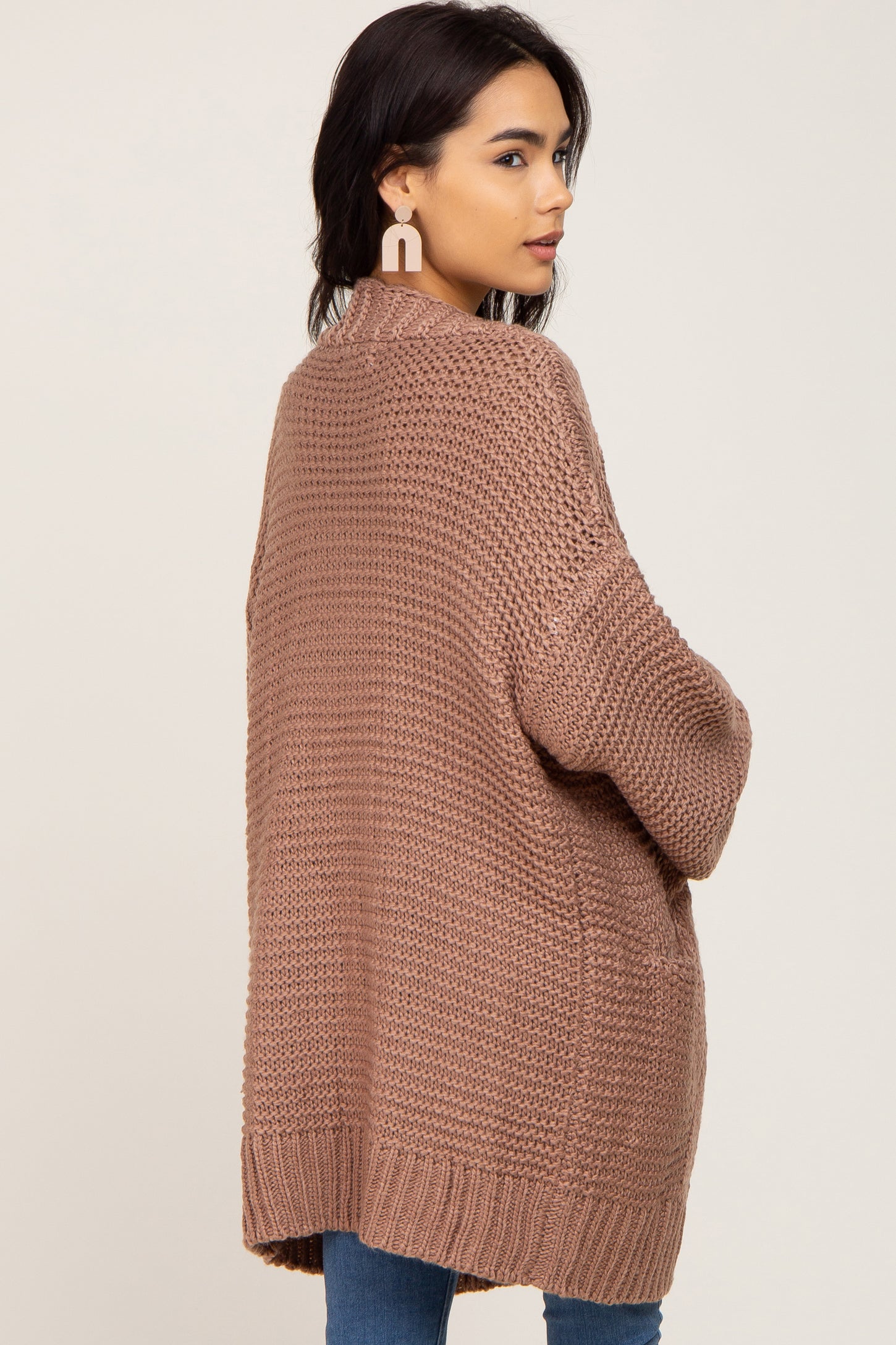 woman wearing a mauve oversized chunky knit cardigan sweater with arch earrings