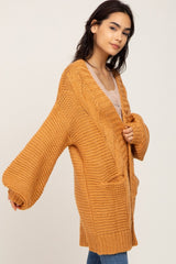 woman wearing oversized mustard yellow chunky knit cardigan with balloon sleeves and front pockets