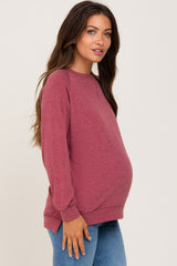 pregnant woman wearing a long sleeve burgundy maternity sweatshirt and blue jeans