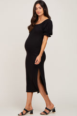 Pregnant woman wearing a black ribbed maternity midi dress with puff sleeves and a side slit