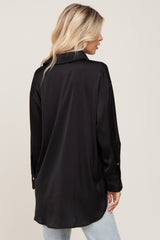 Back view of a woman with blonde hair wearing a black long-sleeve satin button-down shirt and light wash jeans