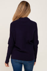 back view of a woman with blonde hair wearing a navy blue ribbed knit sweater and blue jeans