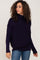 woman with curly hair wearing a navy blue ribbed turtleneck sweater and blue jeans