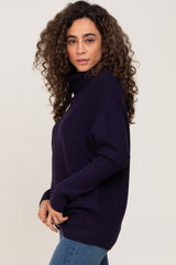 woman with long curly hair wearing a navy blue turtleneck ribbed sweater and denim jeans