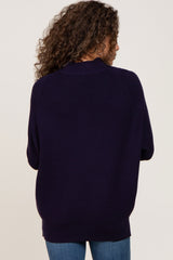 Back view of a woman with curly hair wearing a dark navy blue ribbed knit sweater and blue jeans