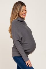 pregnant woman wearing a grey ribbed turtleneck maternity sweater and blue jeans