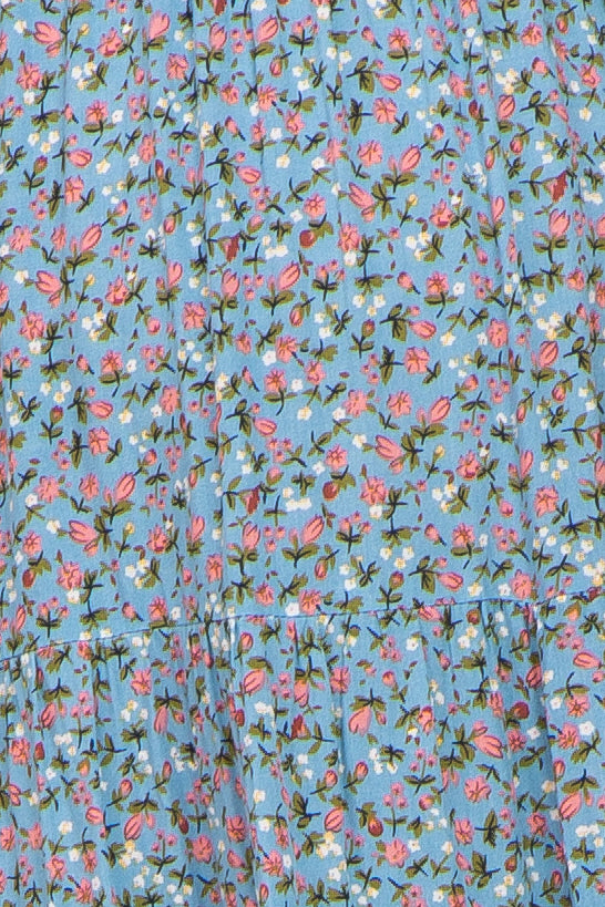 Close-up of light blue fabric with a pink and white ditsy floral print and tiered seam detail