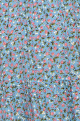 Close-up of light blue fabric with a pink and white ditsy floral print and tiered seam detail