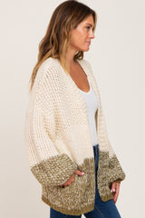 woman wearing cream and olive green colorblock chunky knit cardigan with oversized sleeves