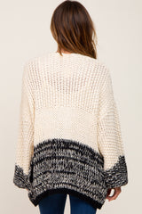 Back view of a woman wearing a cream and black colorblock chunky knit cardigan sweater